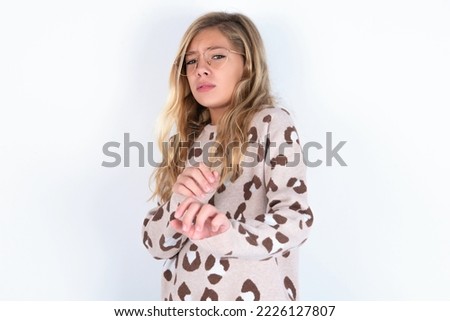 Ugh how disgusting! Displeased caucasian teen girl wearing animal print sweater over white background , has dissatisfied facial expression as sees something abominable.