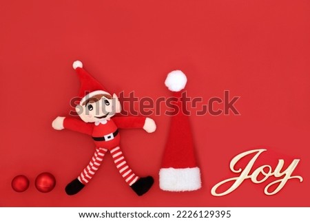 Christmas eve joy sign on red background with santa symbols of elf, hat, tree ball bauble decorations  Fun exciting abstract Xmas happiness concept for the holiday season.