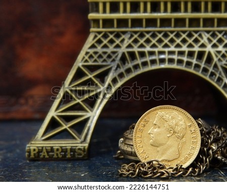 
Gold coin 20 francs 1814 France Napoleon against the background of a bronze model of the Eiffel Tower symbols of France selective focus					