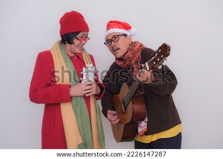 Man and woman standing and celebrating Christmas singing together. Merry Christmas 2022