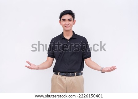 A friendly young man with his arms open as if to welcome someone. A supervisor in a black polo shirt and khakis. Isolated on a white background. Royalty-Free Stock Photo #2226150401