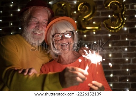 Beautiful caucasian senior couple holding sparklers celebrating new year. Happy lifestyle for mature retirees, party lights