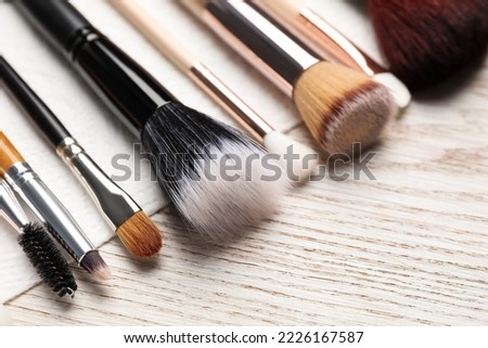 Clean makeup brushes with napkin on wooden table, closeup Royalty-Free Stock Photo #2226167587