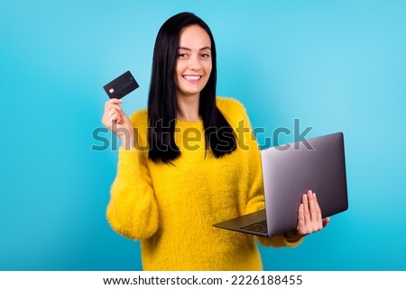 Photo of amazing pretty woman hold new model laptop buy online use credit card wear yellow pullover isolated blue color background
