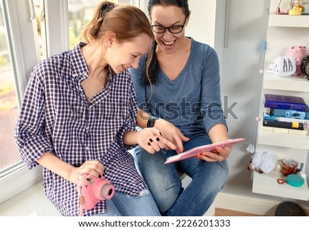 Mom and daughter look at a photo album at home and have fun