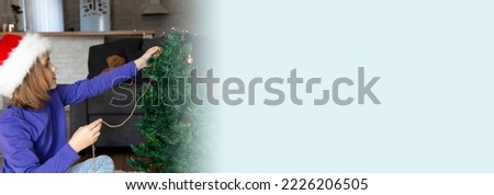 Banner. A cute little girl in a Santa hat is decorating the Christmas tree, hanging balloons and a garland on the Christmas tree. The concept of family winter holidays and traditions