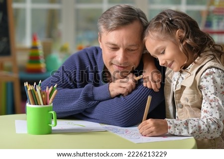 Portrait of father with cute daughter draw at home