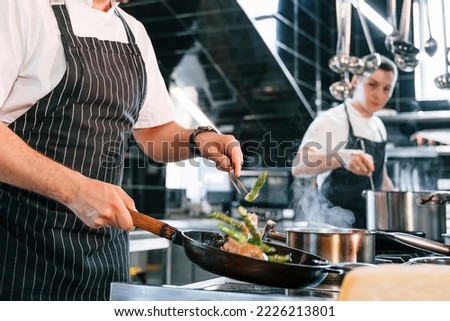 Side view. Kitchen workers is together preparing the food. Royalty-Free Stock Photo #2226213801