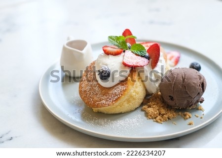 Close-up fluffy Japanese soufflé pancakes with mixed berries and chocolate ice cream dessert served with honey sauce. Royalty-Free Stock Photo #2226234207