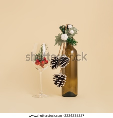 Minimal winter holidays composition. Red wine bottle and glass with natural decoration. Christmas and New Year concept.