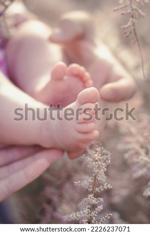 Close up barefooted newborn concept photo. Beauty of maternity. Side view photography with mother hand on background. High quality picture for wallpaper, travel blog, magazine, article