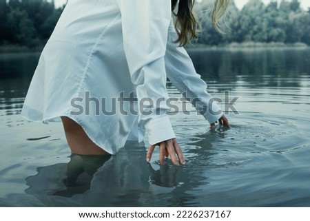 Close up lady touches water concept photo. Beautiful nature. Side view photography with still river on background. High quality picture for wallpaper, travel blog, magazine, article