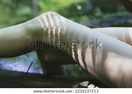 Close up female legs with plants shadow concept photo. Woman knees. Side view photography with pond on background. High quality picture for wallpaper, travel blog, magazine, article