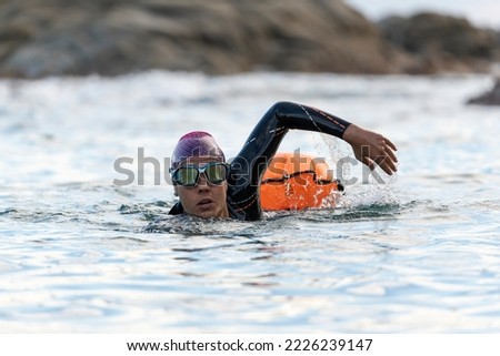 Woman swimming in open water with wetsuit and buoy Royalty-Free Stock Photo #2226239147