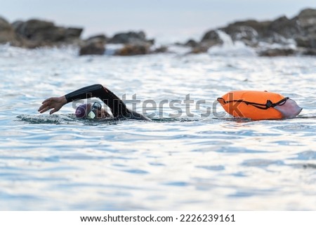 Woman swimming in open water with wetsuit and buoy Royalty-Free Stock Photo #2226239161