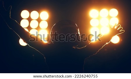 Silhouette of race car driver celebrating the win in a race against bright stadium lights. 100 FPS slow motion shot Royalty-Free Stock Photo #2226240755