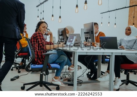 Group of multi-ethnic colleagues working on desktop computers, laptop and sharing their ideas in a modern office space.Young influencers work on online marketing projects.