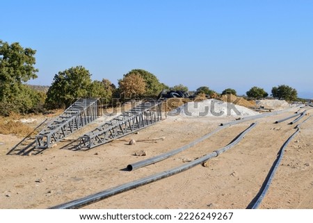 Electricity pilon and water pipes standing in the construction area