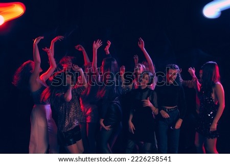 Group of young people attending party, dancing, having fun over dark background in neon light. Disco club activity. Concept of youth culture, leisure time activity, fun, lifestyle, communication