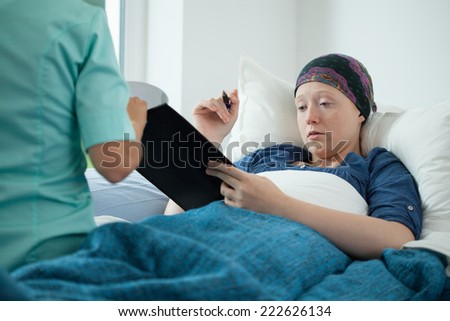 Cancer young woman signing documents in hospital