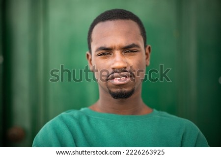 Close up portrait of handsome young african man in green t-shirt staring at camera
