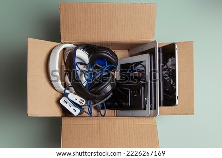 Cardboard box full of old used laptop computers, digital tablets, smartphones, power bank for recycling on gray background. Donation, e-waste, electronic waste for reuse, refurbish and recycle concept Royalty-Free Stock Photo #2226267169