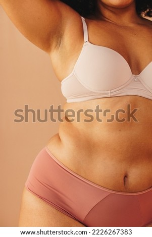 Unrecognisable plus size woman standing against a studio background in underwear. Body positive young woman feeling comfortable in her natural body and curves. Royalty-Free Stock Photo #2226267383