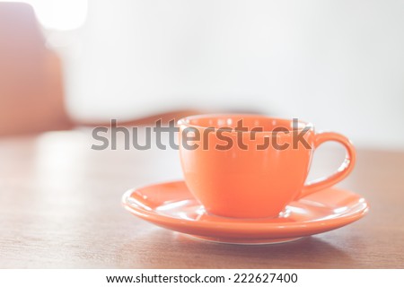 Mini orange coffee cup on wooden table, stock photo