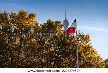 Visit Paris. Photo with the national flag of France against blue sky autumn landscape with Eiffel Tower landmark in background.