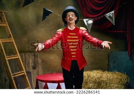 Smiling illusionist or showman. Happy excited man retro circus entertainer announces start of show isolated over dark retro circus backstage background. Concept of emotions, art, sales Royalty-Free Stock Photo #2226286141