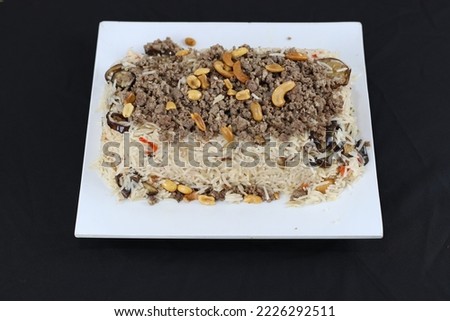 Serving Plate of Maqlooba Rice Food with meat and nuts topping | Hi-Res Stock Photos And Images