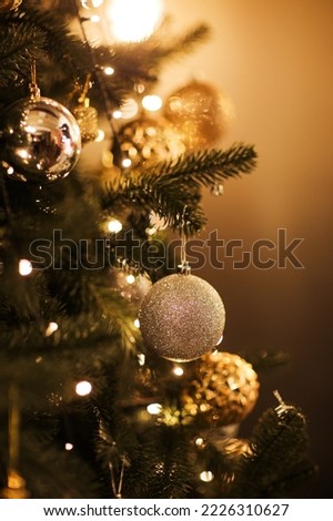Close up view of beautiful fir branches with shiny golden bauble or ball, xmas ornaments and lights, Christmas holidays background. copy space. Decoration on christmas tree. Festive new 2023 year.