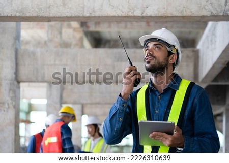 maintenance manager using a walkie-talkie to communicate safety and quality control policy with workers on site, civil engineer informs infrastructure and building construction progress to supervisor Royalty-Free Stock Photo #2226310639