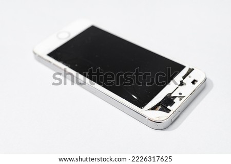 Smartphone with broken screen isolated on gray background. Damaged mobile phone