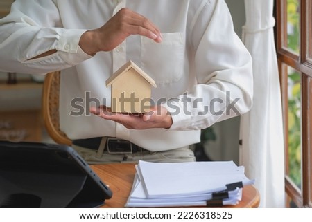 Accountant, businessman, real estate agent, Businessman handing model house to customers along with house interest calculation documents for customers to sign.