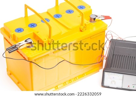 yellow car battery with car battery charger isolated on white background.