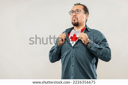 Fan man of 40s proud to show the jersey of the soccer team of his country Canada under his shirt, on white background