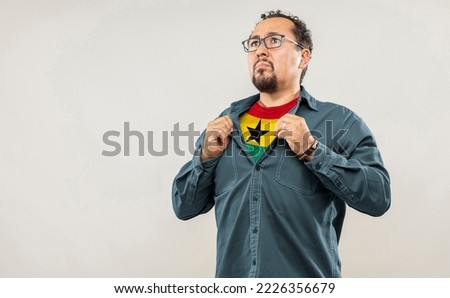 Fan man of 40s proud to show the jersey of the soccer team of his country Ghana under his shirt, on white background