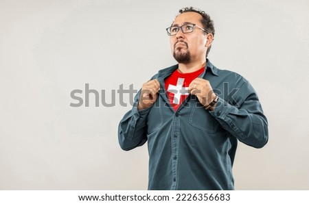 Fan man of 40s proud to show the jersey of the soccer team of his country Switzerland under his shirt, on white background