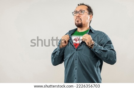 Fan man of 40s proud to show the jersey of the soccer team of his country IR IRAN under his shirt, on white background Royalty-Free Stock Photo #2226356703