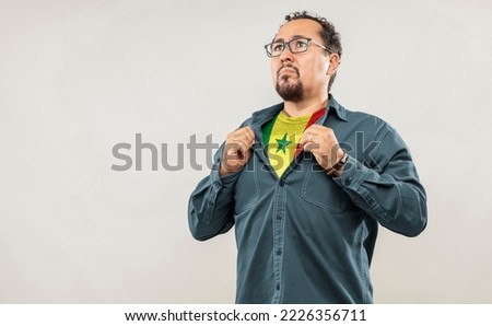 Fan man of 40s proud to show the jersey of the soccer team of his country Senegal under his shirt, on white background