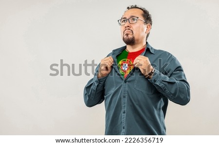 Fan man of 40s proud to show the jersey of the soccer team of his country Portugal under his shirt, on white background