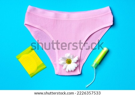 Women's panties with sanitary tampon on color background