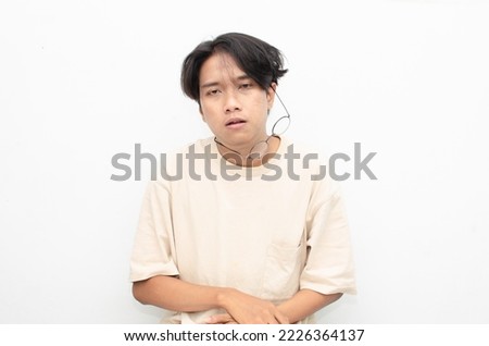 asian man looks depressed and messed up. Irritated man bites lips and scratches head. stressed over work concept. Royalty-Free Stock Photo #2226364137