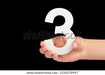 number three in hand isolated on black background. Number three in a child's hand on a black background. To be inserted into a project or design.