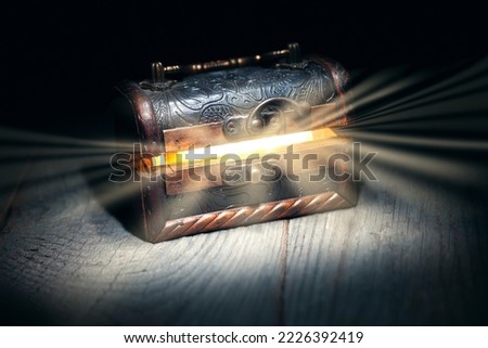 Glowing bright rays of light from an old, open wooden dark brown treasure chest, the concept of a surprise, gift, pandora's box