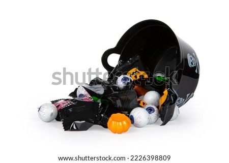 A halloween candy bowl there is tipped over to the side, with candy falling out, isolated on a white