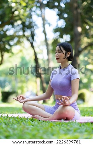 Attractive and strong Asian woman with a beautiful body. meditation relax yoga in an elegant posture in the green park Modern concept of relaxation and health care.