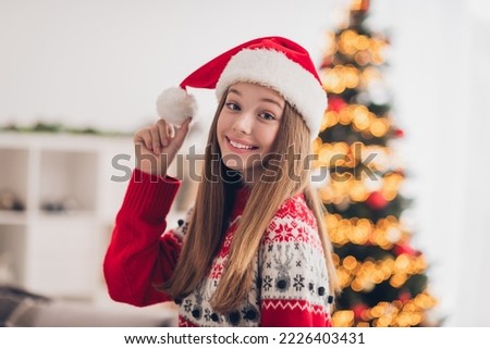 Photo of lovely cheerful girl toothy smile hand touch newyear hat pompom fairy atmosphere indoors