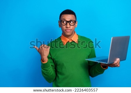 Photo of clever interested man orange shirt green sweatshirt hold laptop indicating look empty space isolated on blue color background